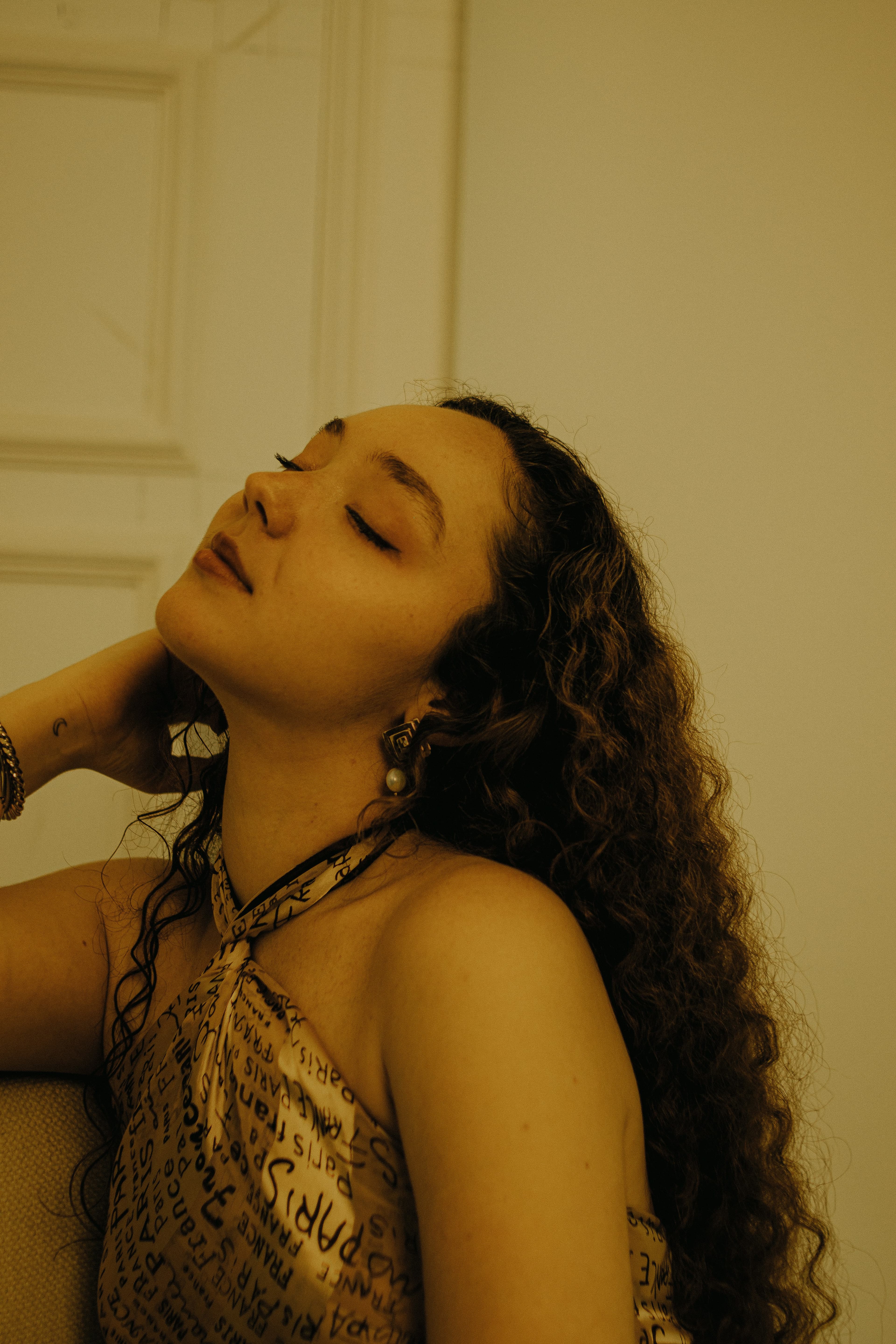 Person with eyes closed, head tilted back in peaceful relief, soft golden light on face
